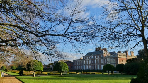 Wimpole Hall sits within a winter scene on a bright day, the trees are bare and the sky is blue